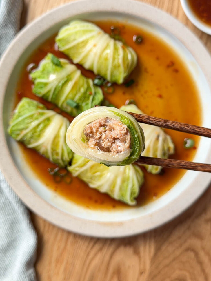 Chinese stuffed cabbage roll with pork and shiitake mushroom filling held with chopsticks